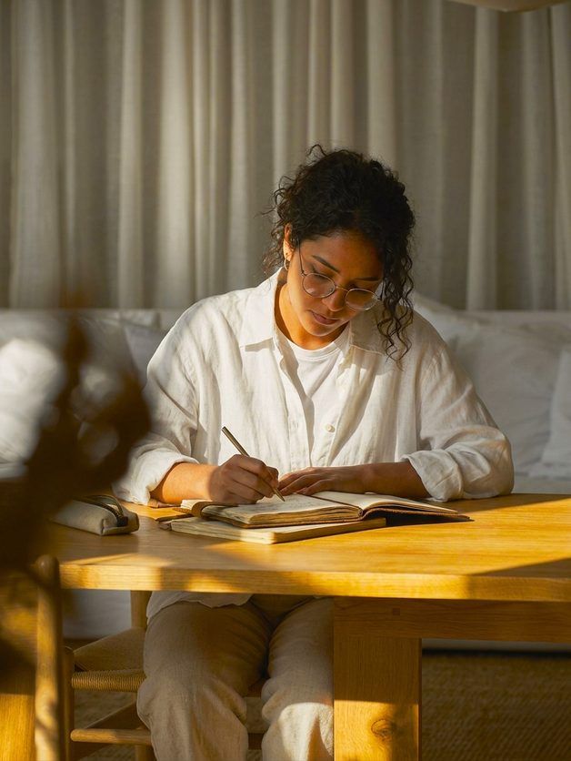 A student writing at a wooden table